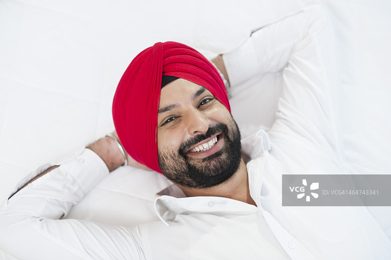一个锡克教男子躺在床上微笑的特写图片素材