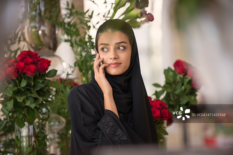 阿拉伯阿拉伯的一名女子拿着红花打电话图片素材