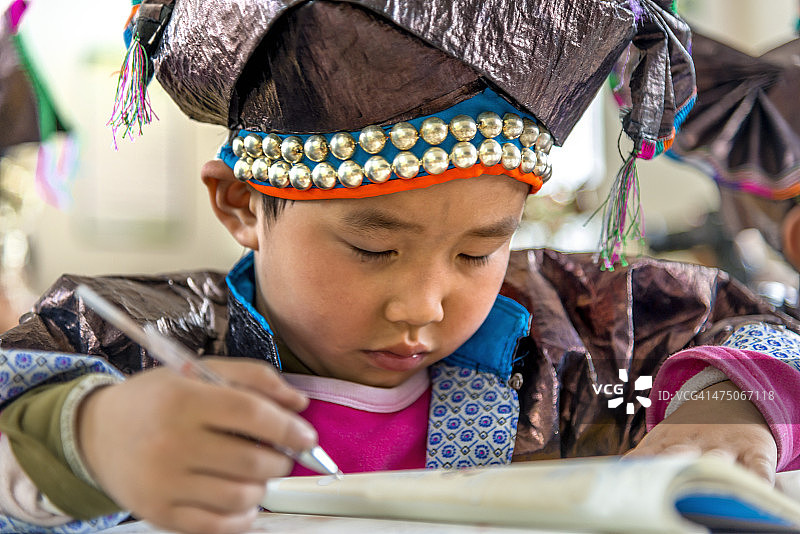 中国男孩穿着传统侗族服装在学校工作图片素材