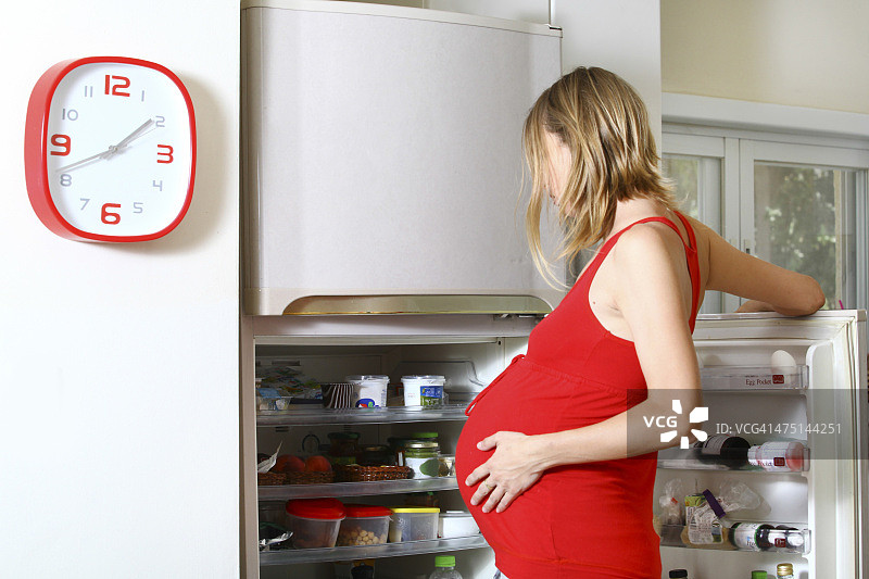 孕妇饥肠辘辘地看着冰箱图片素材
