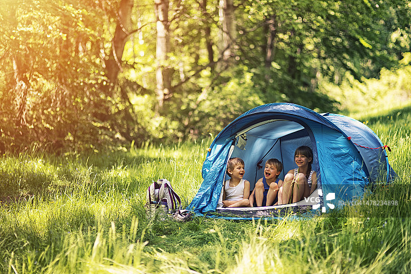 徒步旅行者的孩子们坐在森林里的帐篷里图片素材