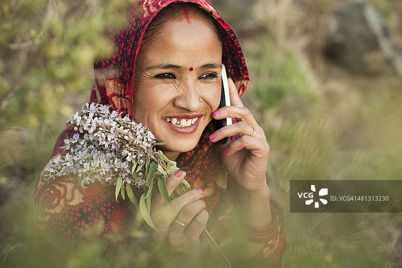 快乐的传统亚洲妇女使用电话在农村的自然。图片素材