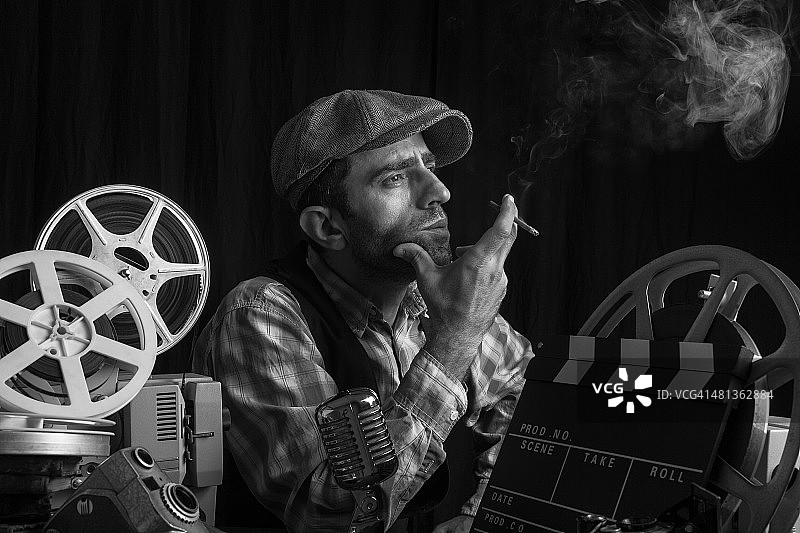 老式电影导演与电影设备摆姿势和吸烟图片素材