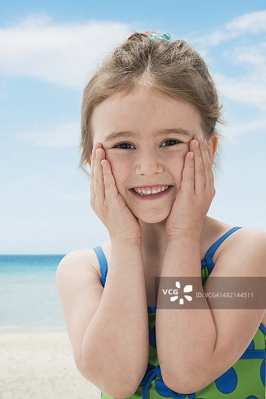 微笑的女孩的肖像与手在海滩上图片素材