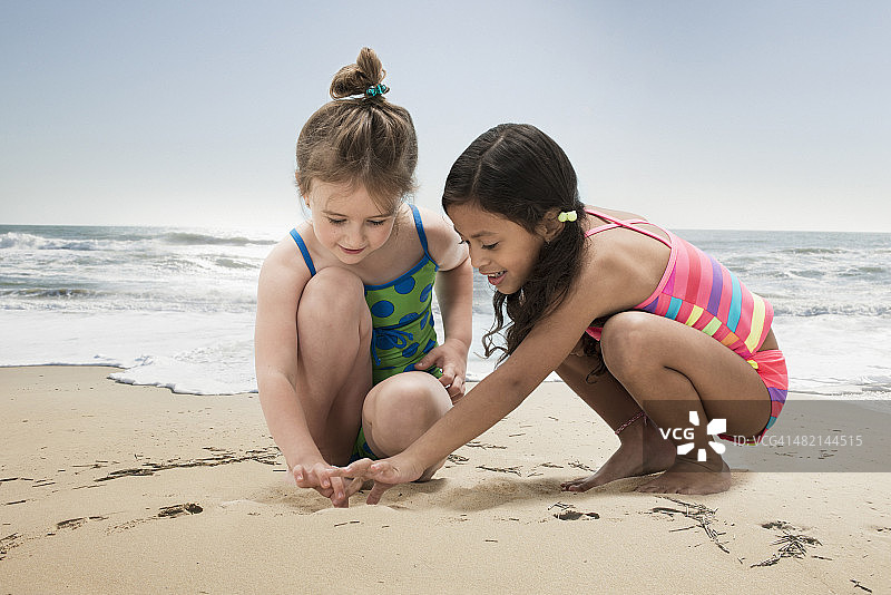 女孩们在沙滩上画沙子图片素材