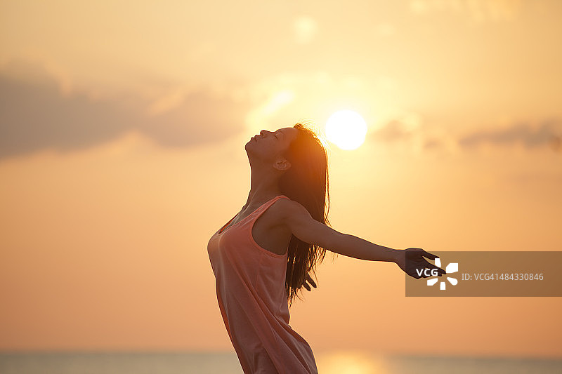 亚洲女人在日出的海滩上图片素材