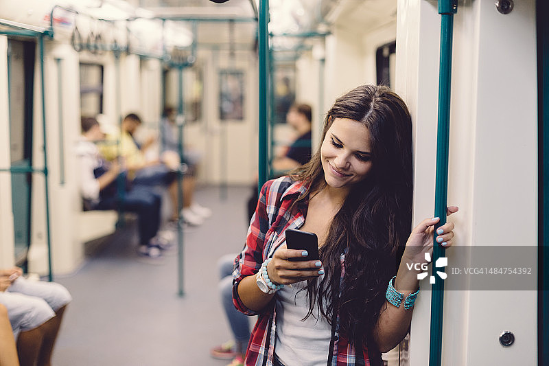 十几岁的女孩在乘坐地铁时使用手机图片素材