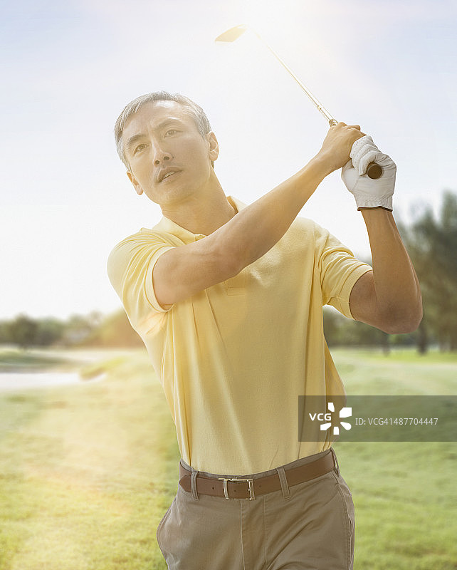 中国男子在球场上打高尔夫球图片素材