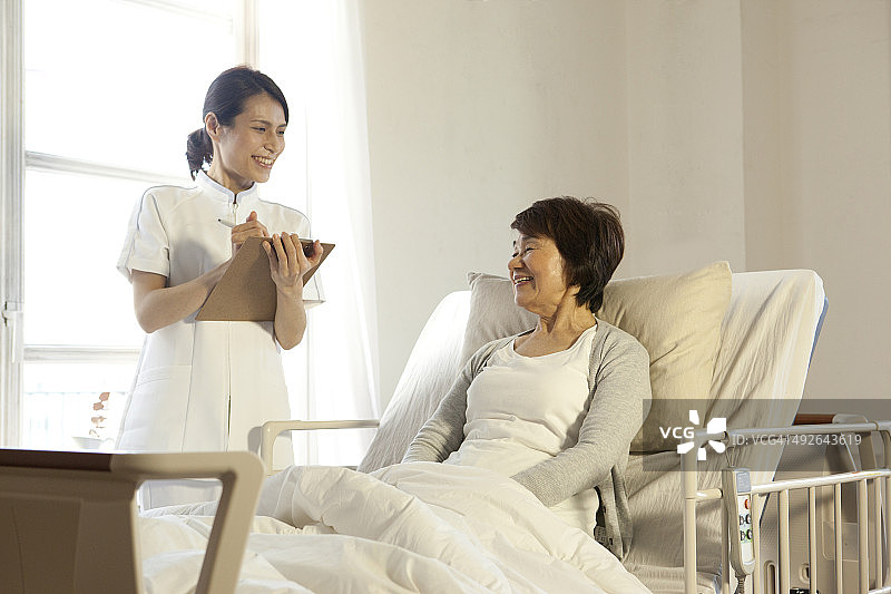 女护士在床上对着老女人微笑图片素材