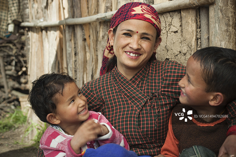 亚洲，尼泊尔，传统的快乐的农民妇女和她的两个孩子。图片素材