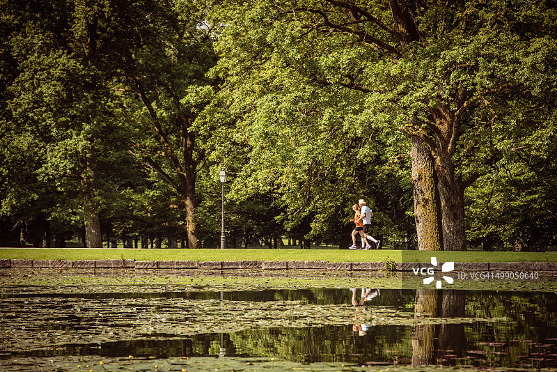 一对慢跑者在湖边的公园里跑步图片素材