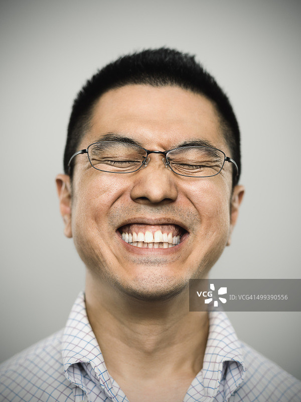 一个快乐的日本年轻人看着照相机的肖像图片素材