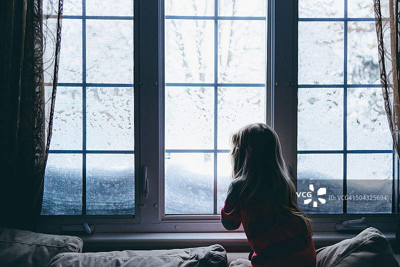 小女孩望着窗外的雪图片素材