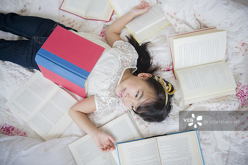 菲律宾女孩躺在床上看书图片素材