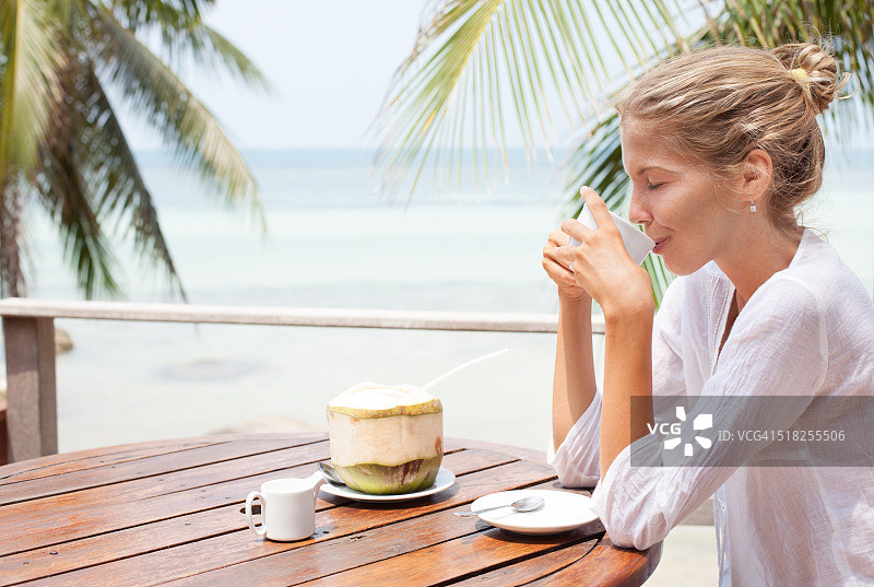 年轻女子喜欢喝咖啡和椰子图片素材