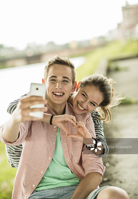 一对幸福的小情侣在用智能手机自拍图片素材