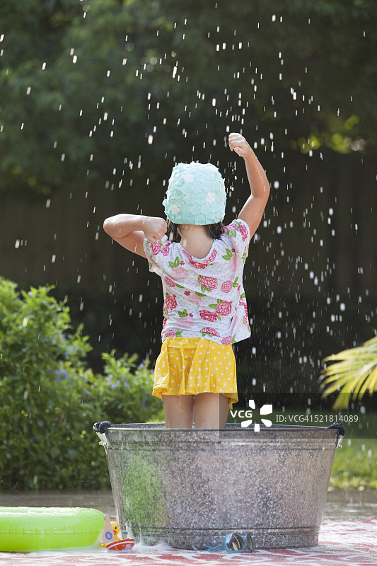 后视图的女孩站在泡沫浴在花园溅肥皂泡泡图片素材