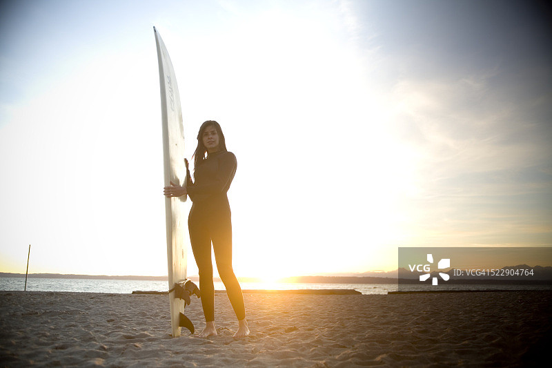 日落时分，冲浪者站在海滩上图片素材