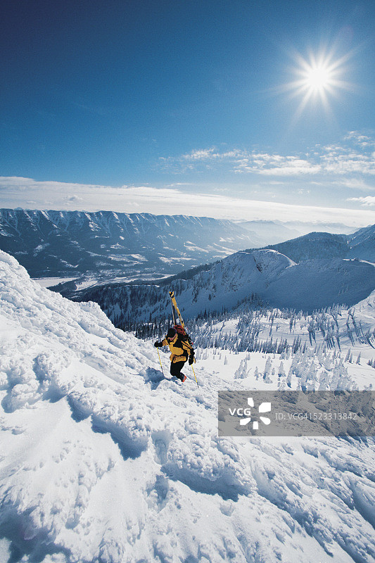 滑雪者扛着滑雪板爬上崎岖的雪山图片素材