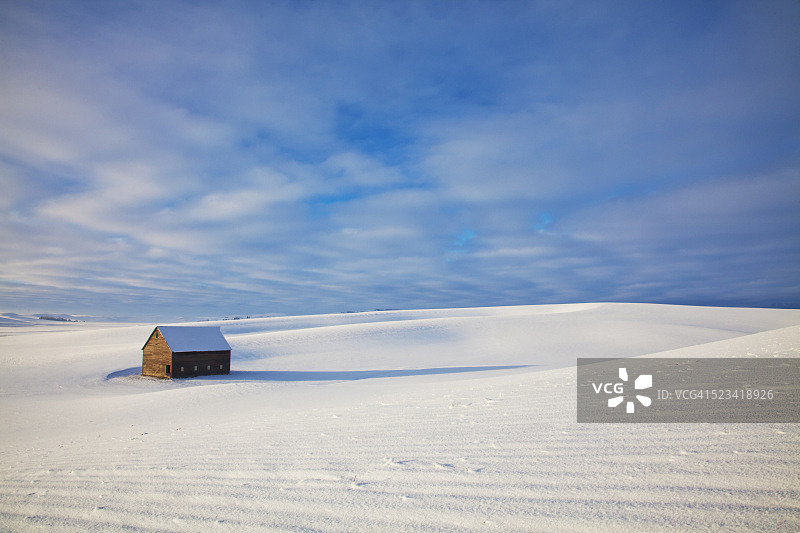 白雪覆盖的田野里的小谷仓图片素材