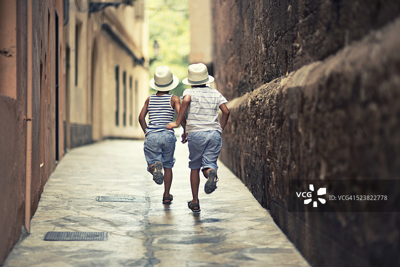 小男孩们在帕尔马的一条狭窄街道上奔跑图片素材