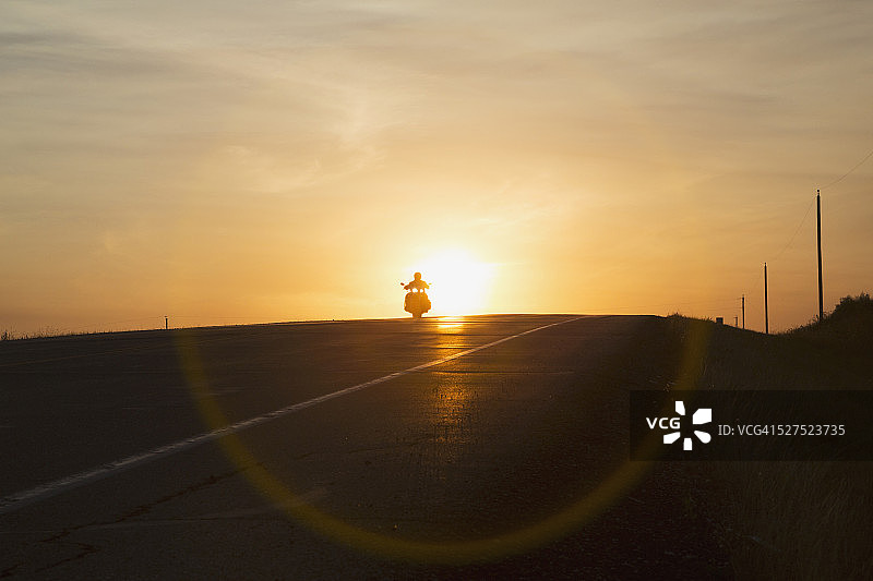 日落时分，埃德蒙顿附近的阿尔伯塔高速公路上，一名男子骑着摩托车图片素材