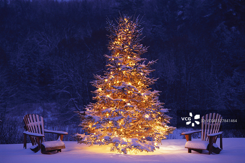 雪覆盖阿迪朗达克椅子，点燃的圣诞树图片素材