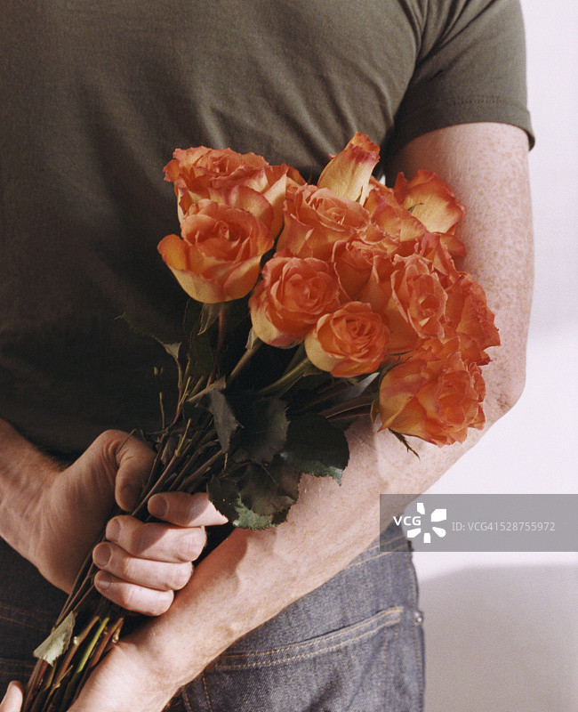 一个男人把一束玫瑰藏在背后图片素材