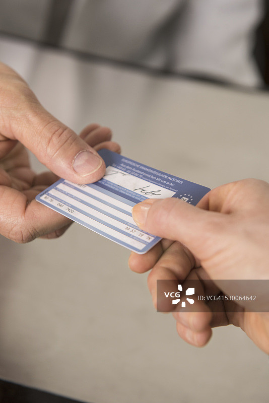 德国，巴伐利亚，慕尼黑，病人将健康保险卡交给医生图片素材