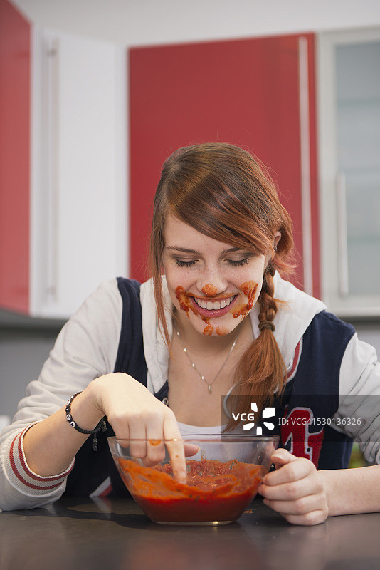 德国巴伐利亚慕尼黑，年轻女子在厨房里吃番茄酱图片素材