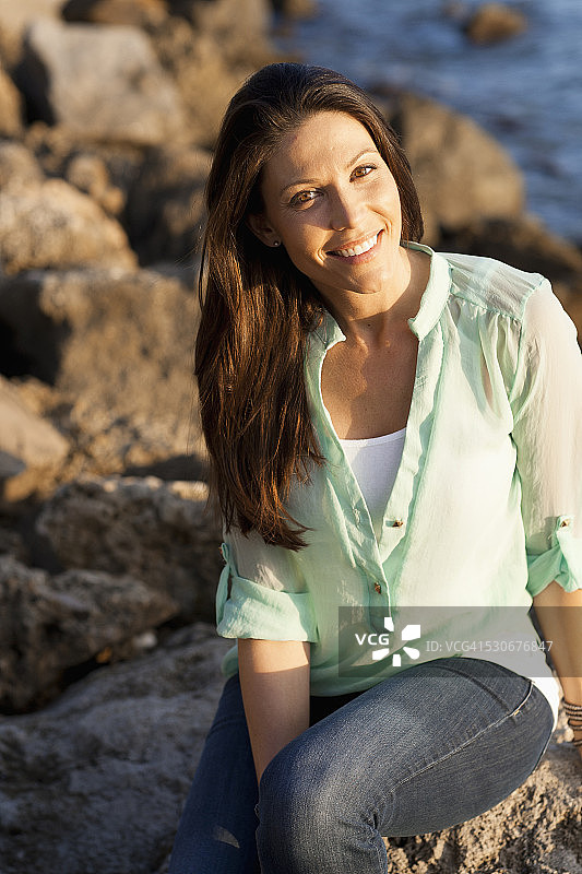 白人女人在岩石海滩上微笑图片素材