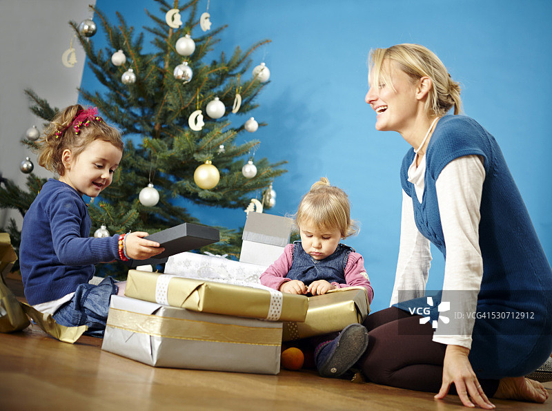 德国巴伐利亚慕尼黑，母亲和两个女孩正在拆圣诞礼物图片素材