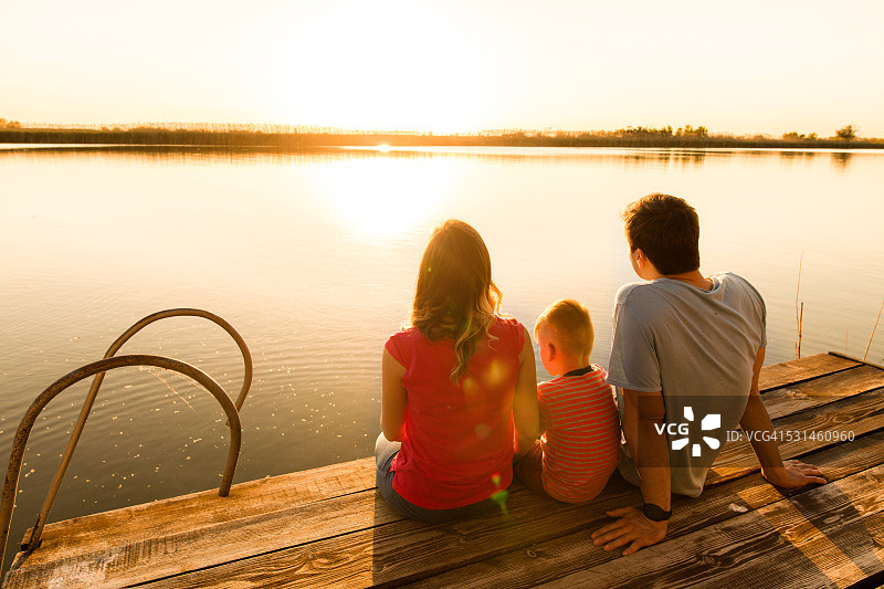 日落时分一家人在码头上放松的背影。图片素材