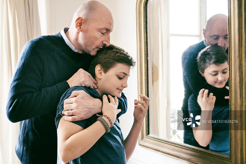 一位法国父亲抱着儿子在镜子前拥抱图片素材