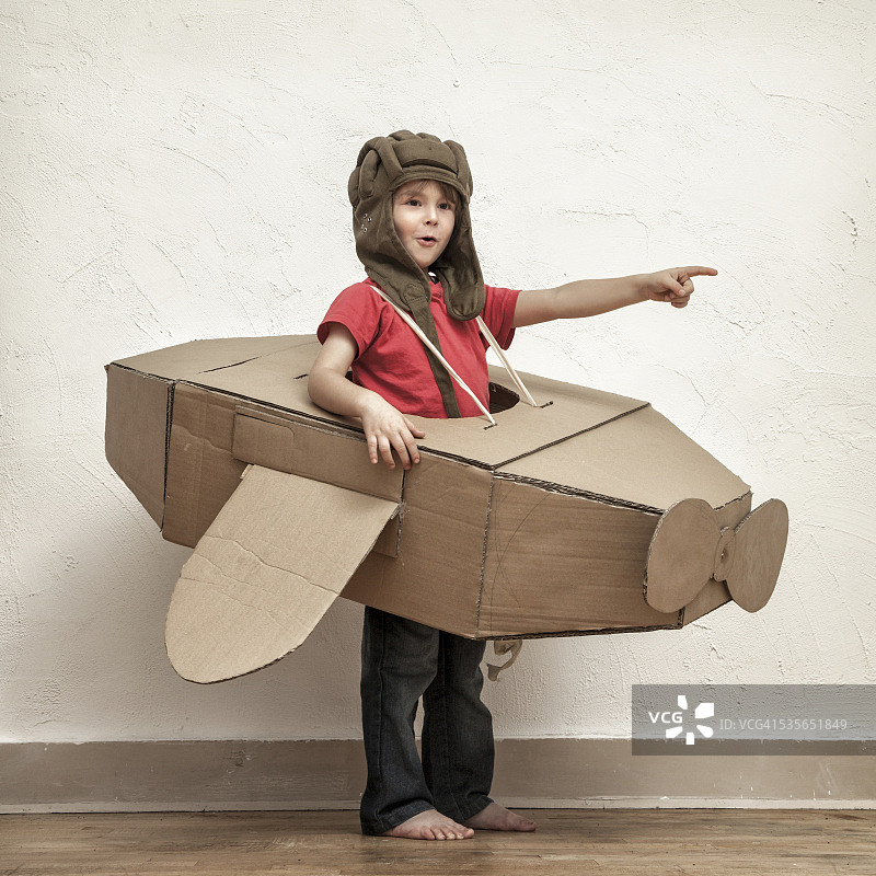 小男孩带着飞行员帽和纸板箱飞机在展示什么图片素材