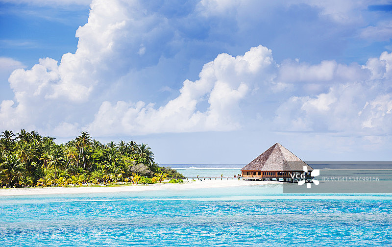 完美热带岛屿上的水上别墅(平房)，热带海滩上美丽的白色沙滩，蓝色的水和蓝天，马尔代夫群岛图片素材
