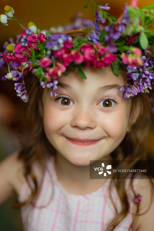 微笑的小女孩戴着花看着相机的肖像图片素材