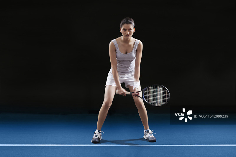 全身的年轻女子在球场上打网球图片素材