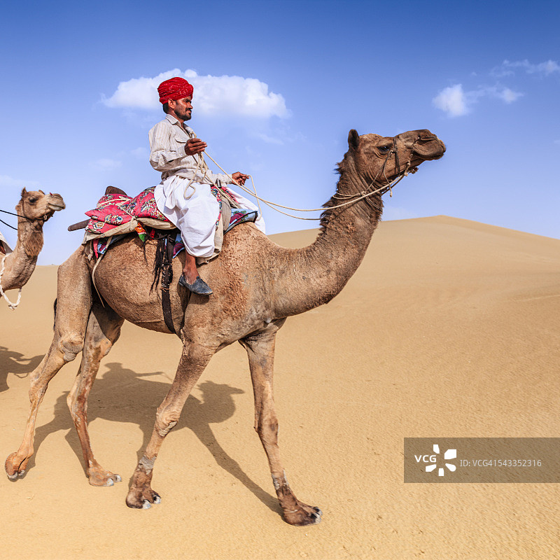 印度拉贾斯坦邦，在沙丘上骑骆驼的印度人图片素材