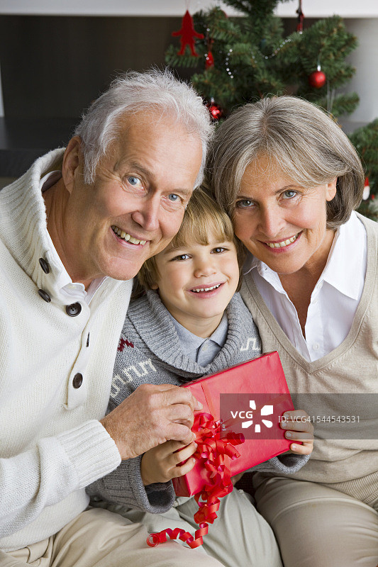快乐的小男孩从他的祖父母收到圣诞礼物图片素材
