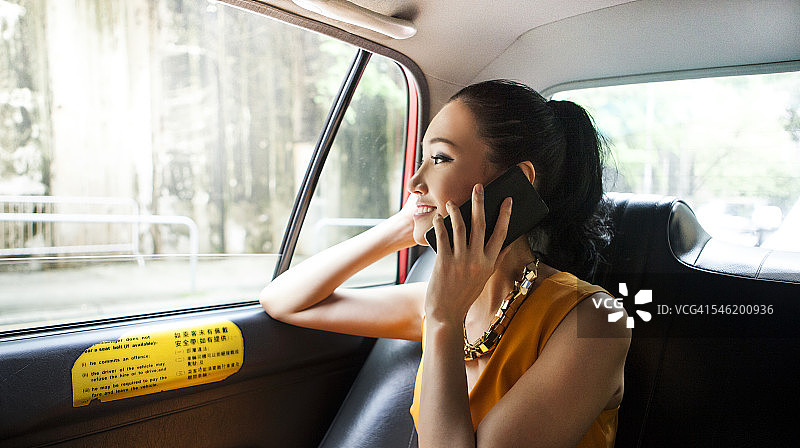 年轻的亚洲女孩在出租车上打电话给她的朋友图片素材