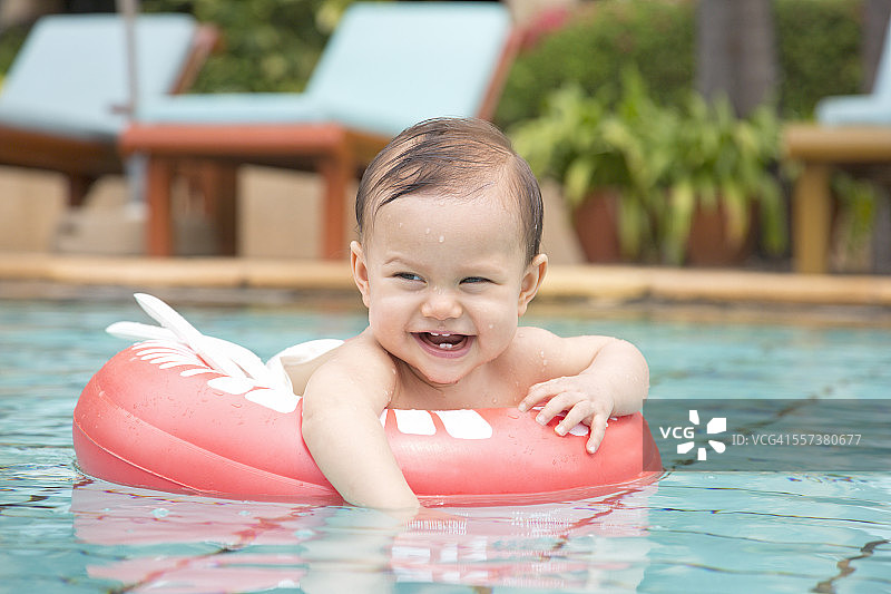 泰国，游泳池里漂浮着轮胎的快乐女婴图片素材