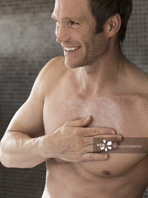 裸露的胸部肌肉男子在浴室摩擦保湿的胸部图片素材