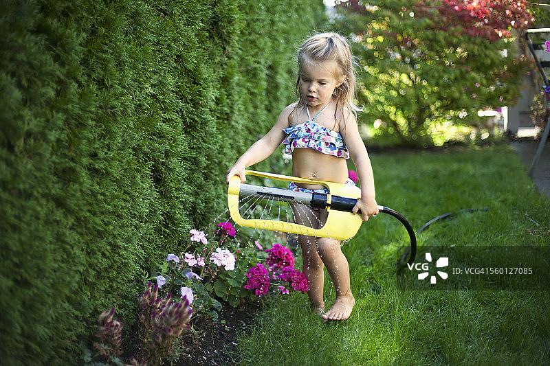 一个在热天享受喷水的年轻女孩图片素材