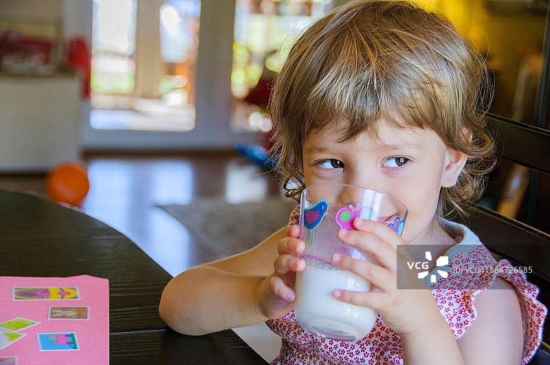 可爱的小女孩在餐桌上喝牛奶的肖像图片素材
