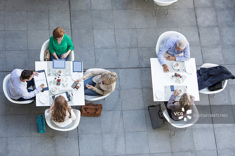 高角度的商人和女商人在酒店阳台上吃工作午餐图片素材