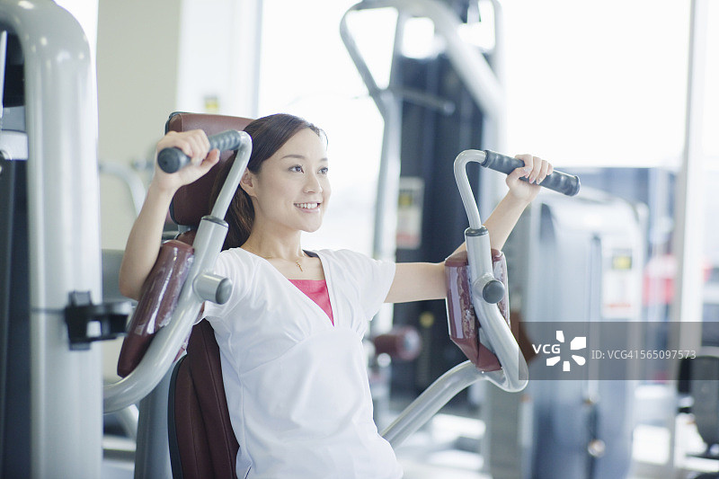 一个女人在健身房的健身机上锻炼图片素材
