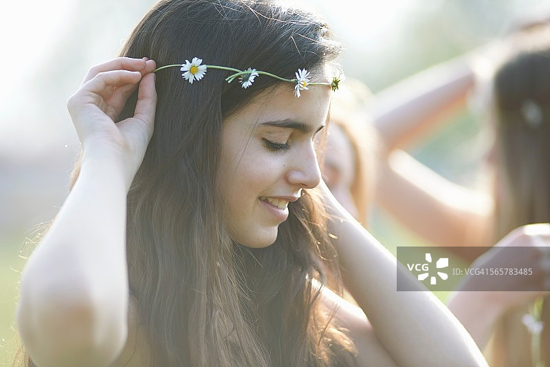 十几岁的女孩在公园戴着雏菊链头饰的肖像图片素材