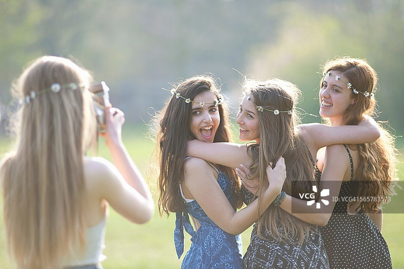 十几岁的女孩在公园里用即时相机拍摄三个朋友图片素材