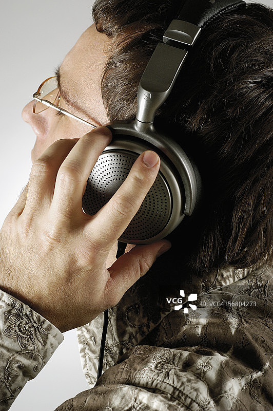 一个年轻人戴着耳机听音乐的特写图片素材